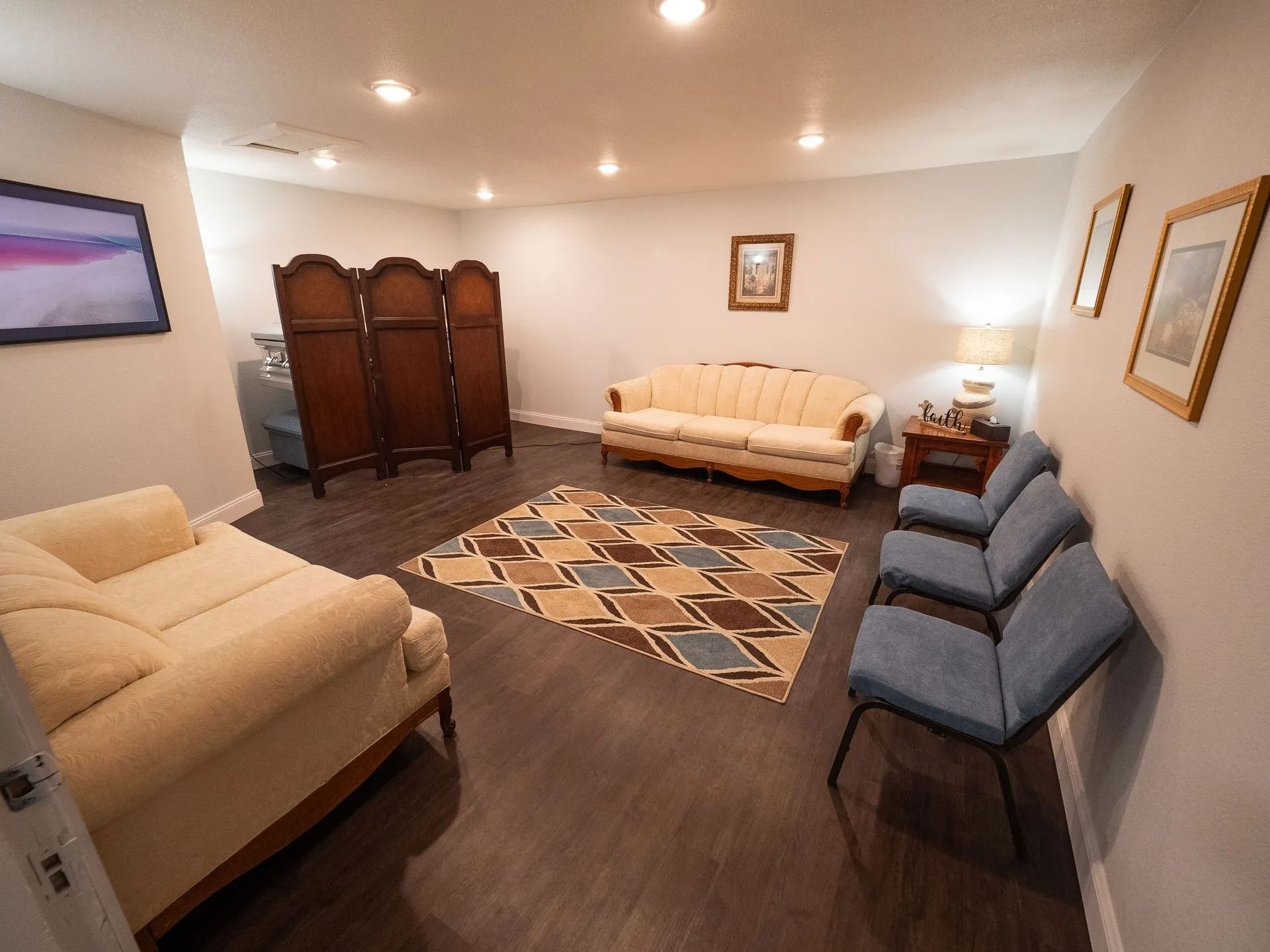 A living room with a couch , chairs , and a screen.