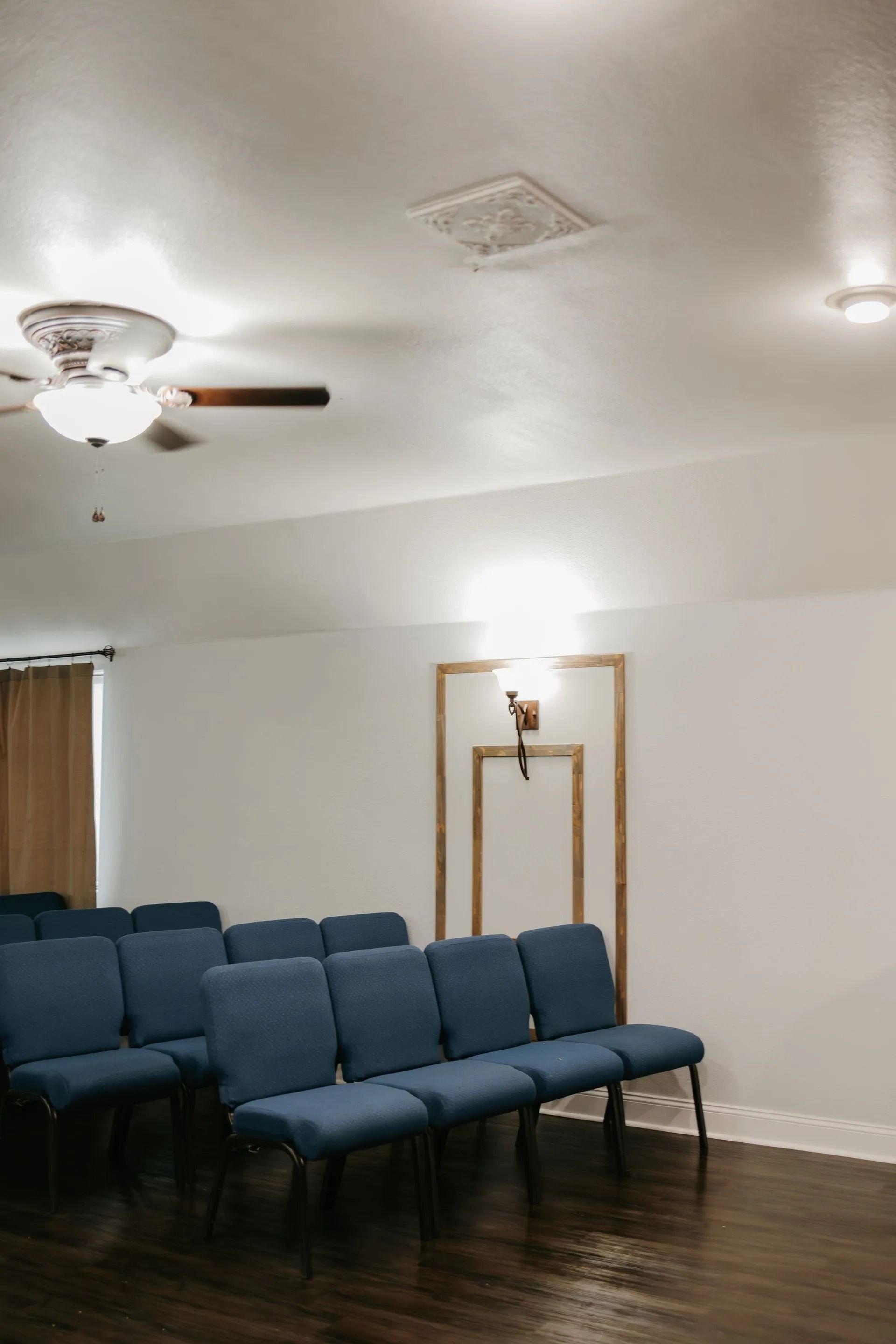 A row of blue chairs in a room with a ceiling fan.