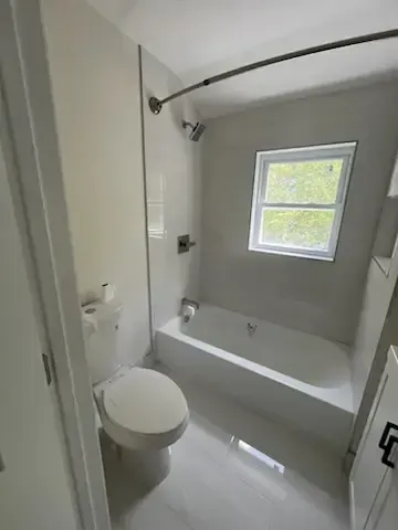 Small bathroom with toilet, bathtub, and a frosted window.