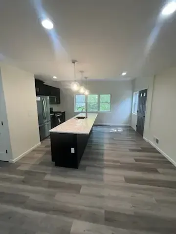 Bright modern kitchen with a large island, gray flooring, white walls, and recessed ceiling lights.