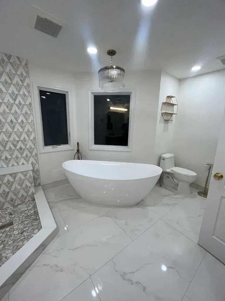 Modern white bathroom with freestanding tub, glass shower, toilet, and marble tile floor.