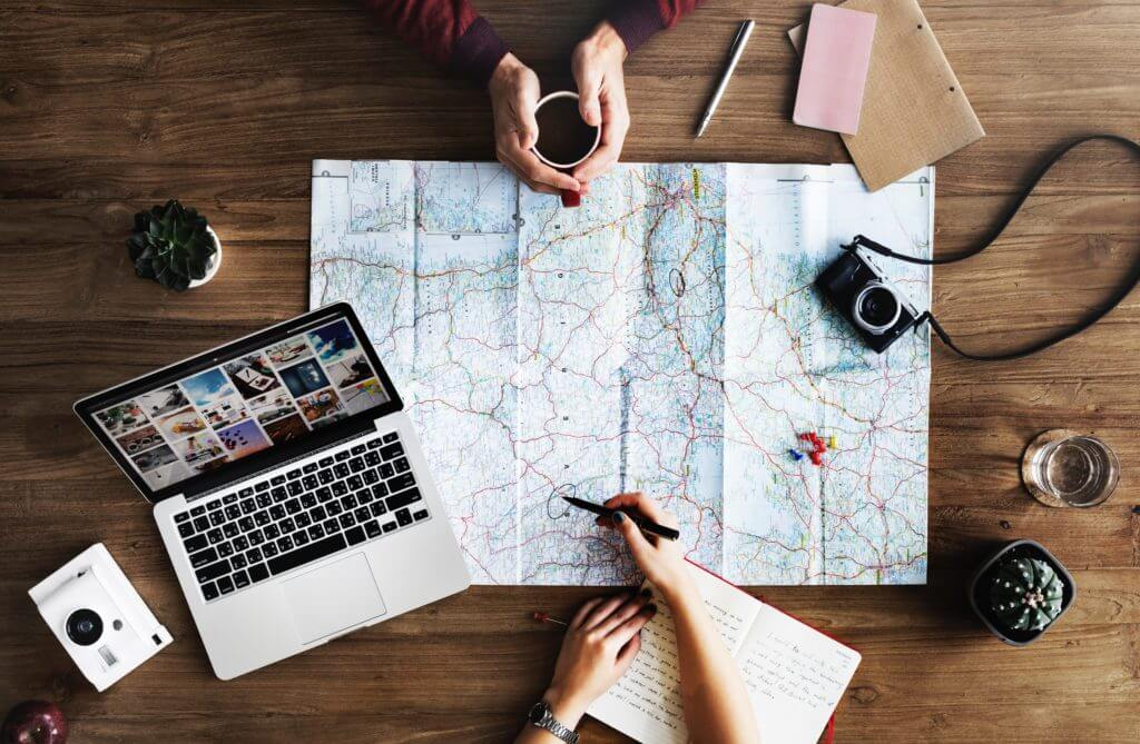 A person is sitting at a table with a laptop and a map.