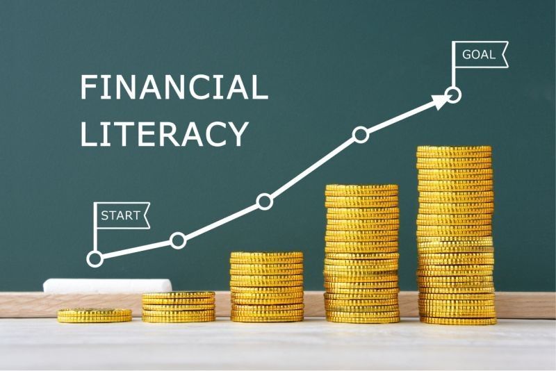 A blackboard with stacks of gold coins and a graph showing financial literacy.