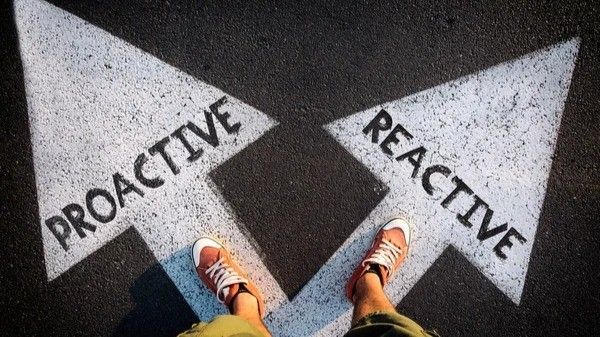 A person is standing in front of two arrows that say proactive and reactive.