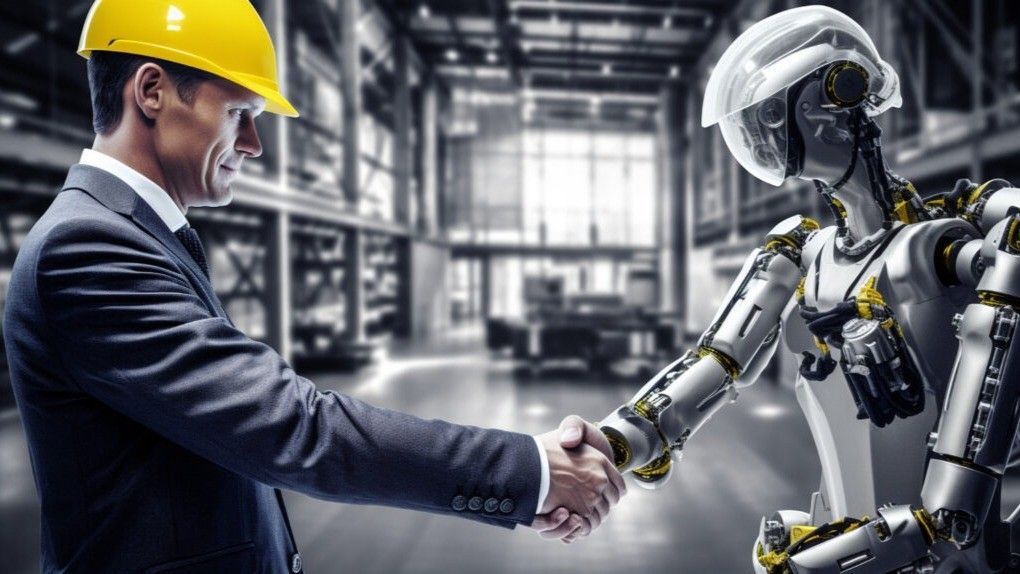 Man in suit and hard hat shakes hands with a humanoid robot in a warehouse setting.