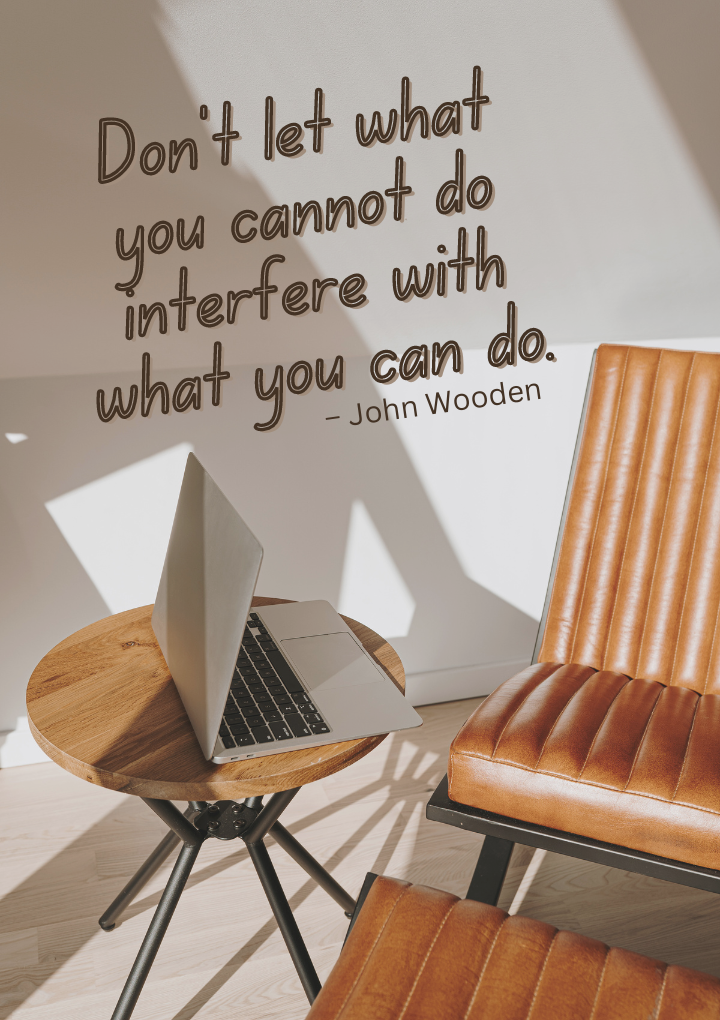 A laptop is sitting on a wooden table next to a quote by john wooden