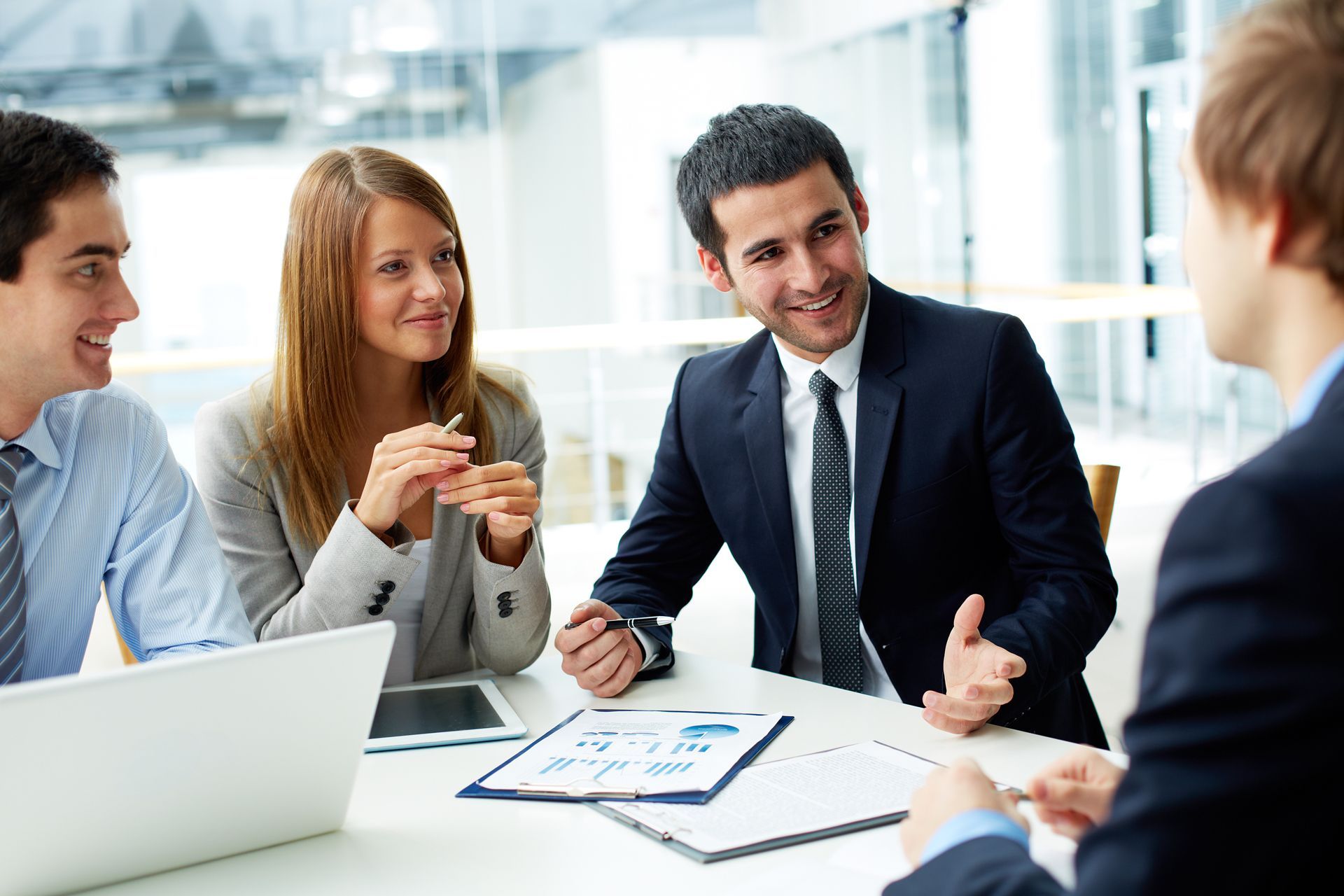 a group of business people are sitting around a table having a meeting