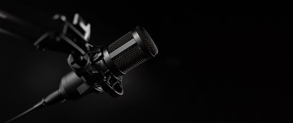 A close up of a microphone on a stand on a black background.