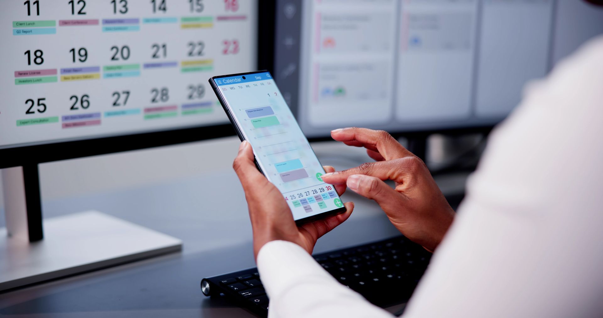 A person is using a cell phone in front of a calendar.