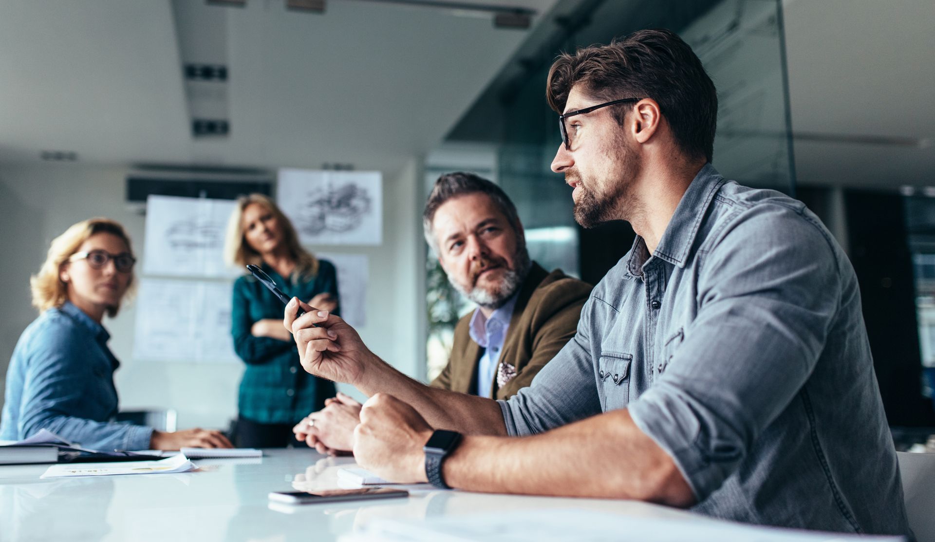 a group of business people are sitting around a table having a meeting