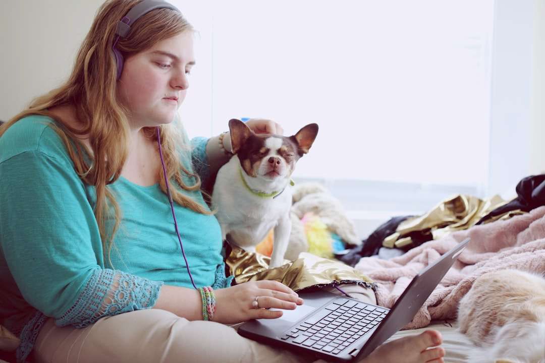 Girl in blue jacket holding white and brown short coated puppy