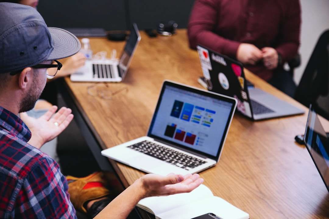 A group of people are sitting at a table with laptops.