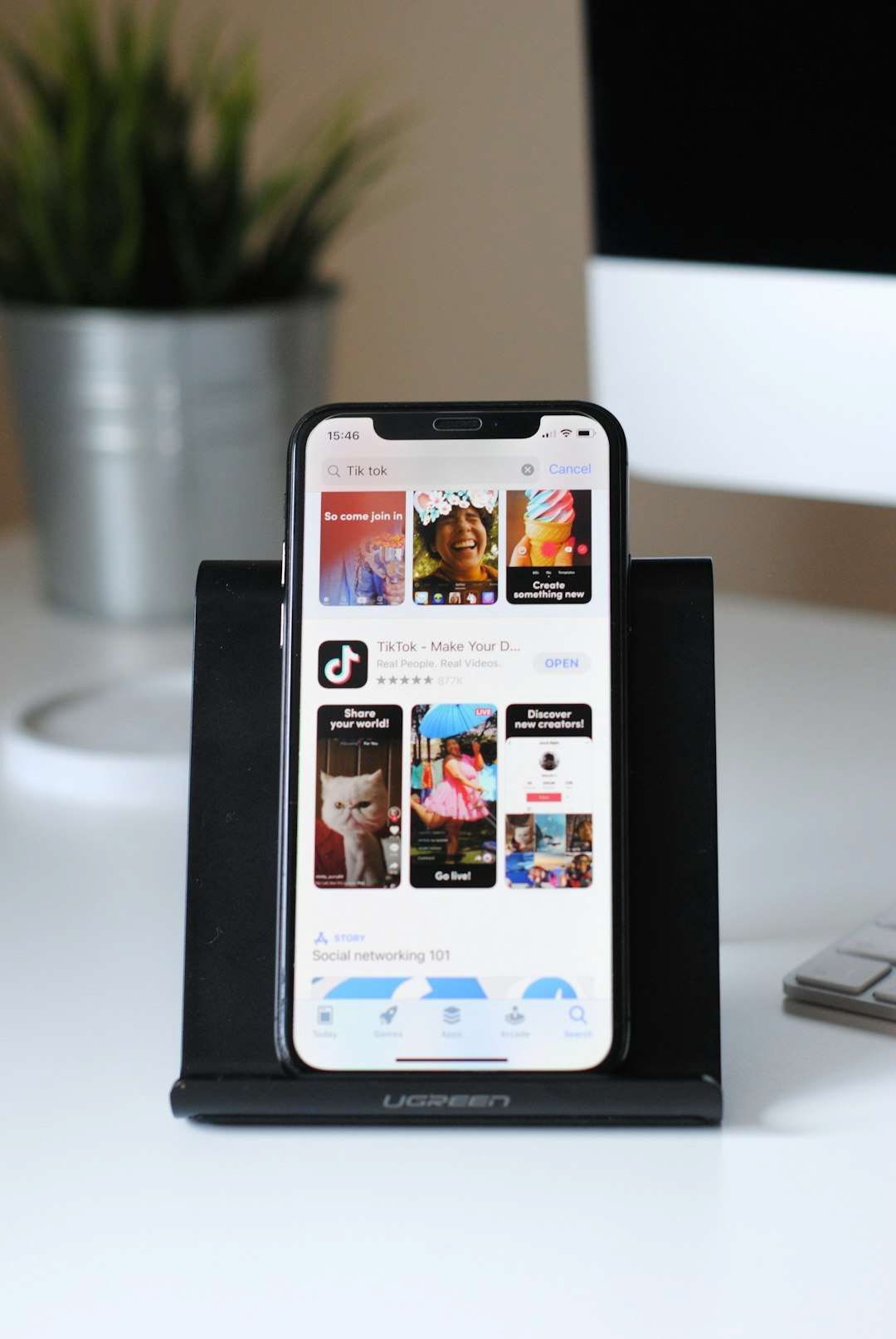 A cell phone is sitting on top of a black holder on a desk.