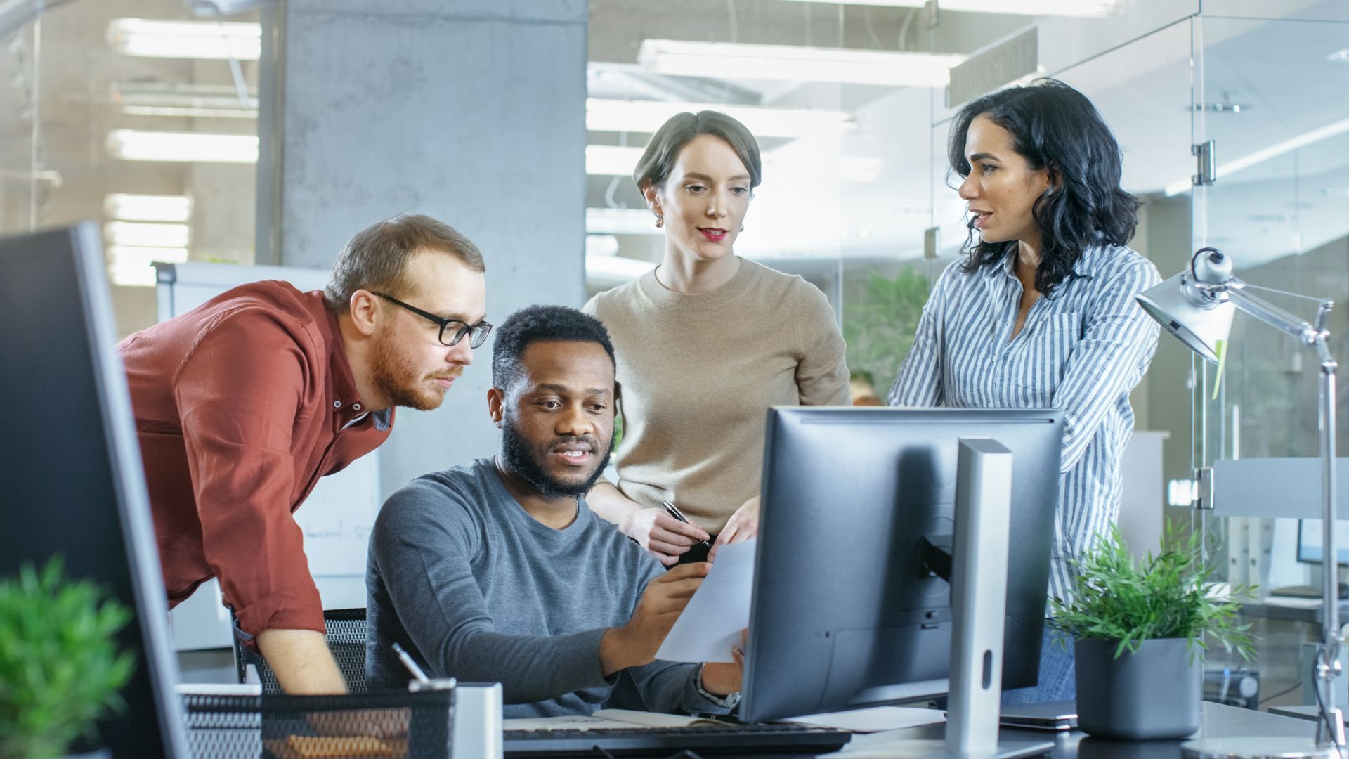 A group of people are looking at a computer screen in an office.