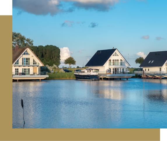 Houses on a lake with a boat; blue sky and water.