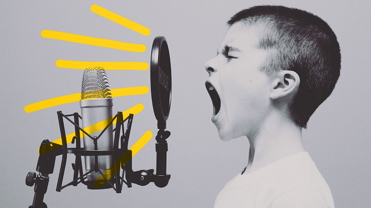 A young boy is singing into a microphone.