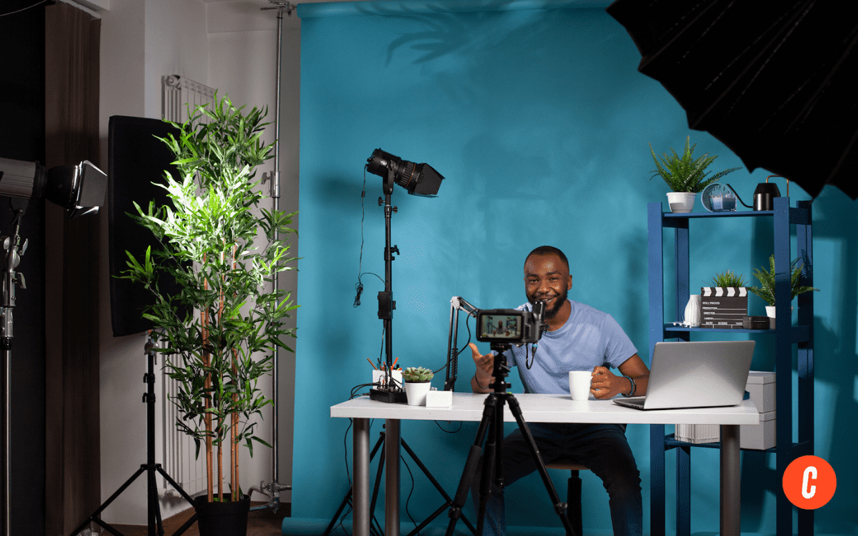 A man is sitting at a desk with a laptop and a microphone.