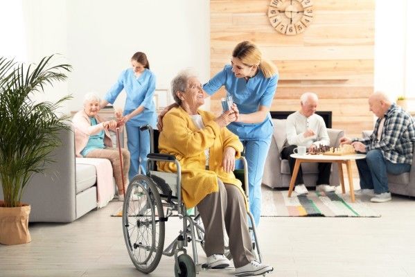 A nurse is helping an elderly man use a walker.