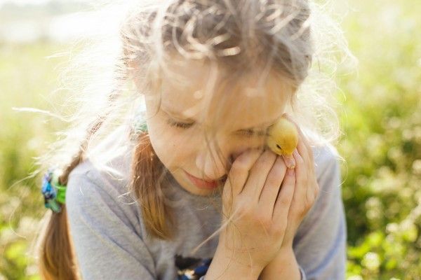 A young girl is holding a small bird in her hands.