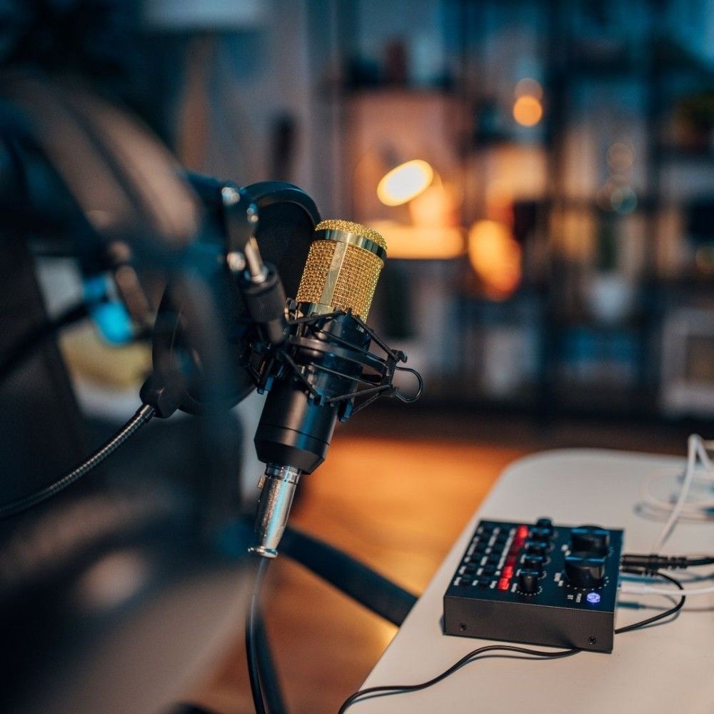 A microphone is sitting on a table next to a mixer.