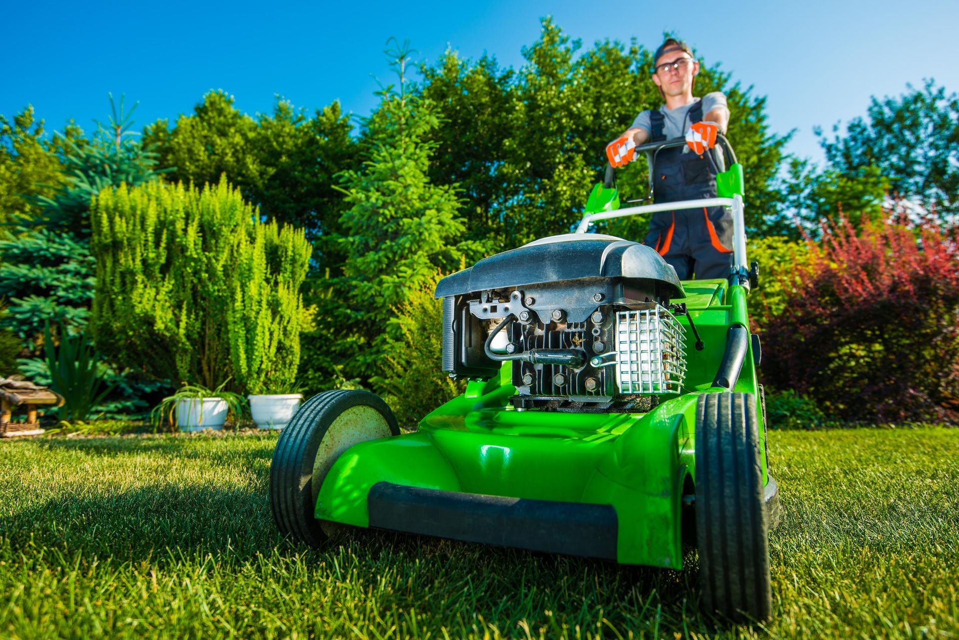 A man is riding a green lawn mower on a lush green lawn.
