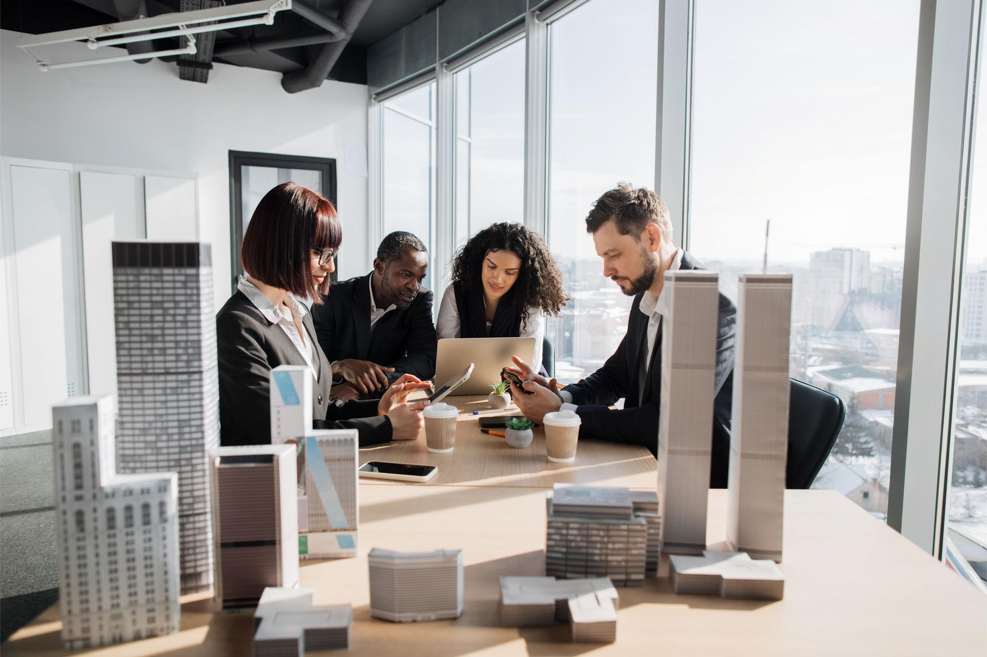 A group of people are sitting around a table with models of buildings on it.