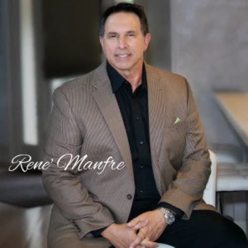 A man in a suit and black shirt is sitting on a chair.