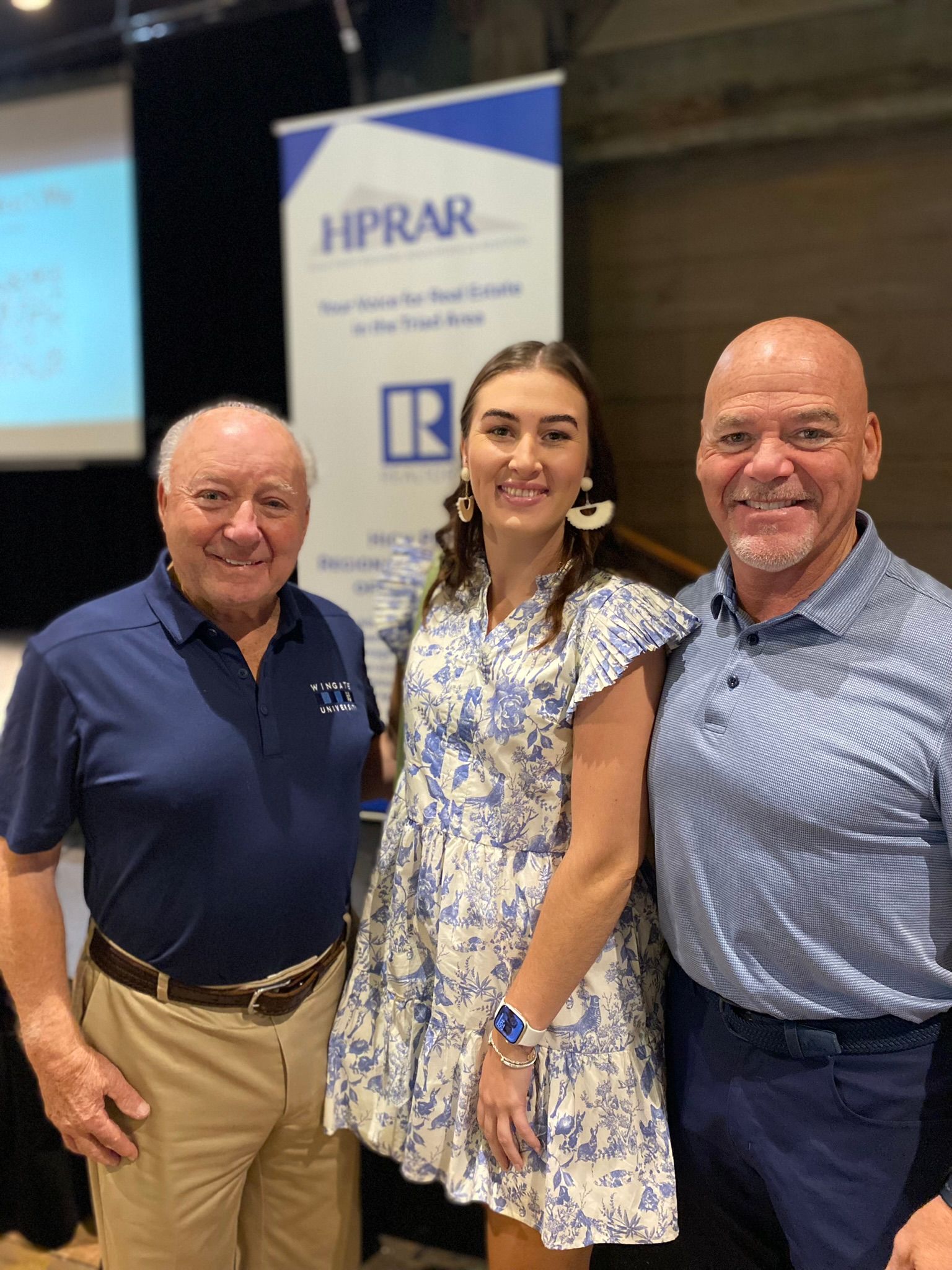 Real estate agent showing house to couple. Woman points right, all smile.