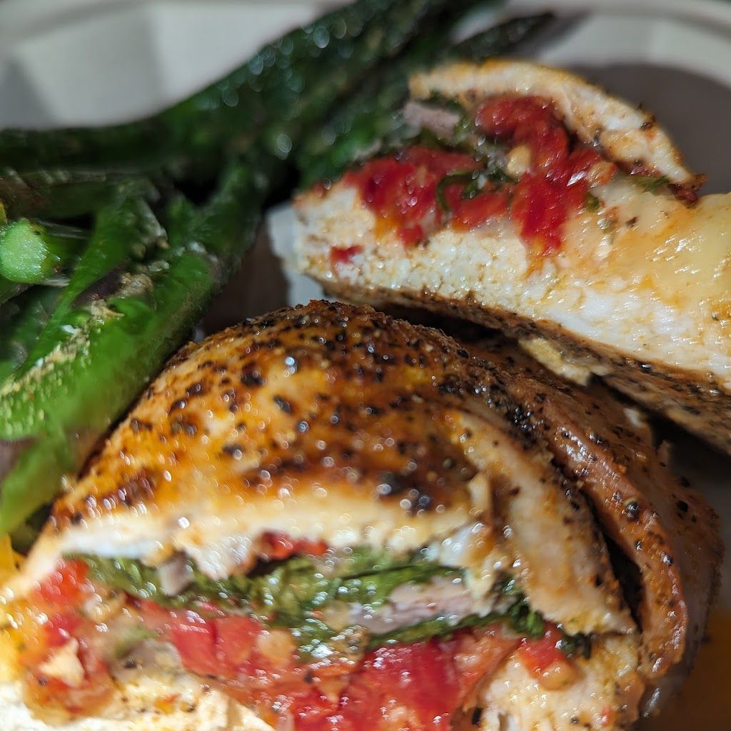A close up of a stuffed chicken breast on a plate with green beans.