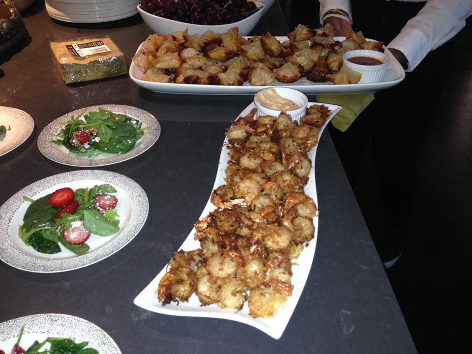 A tray of fried shrimp sits on a table with other plates of food