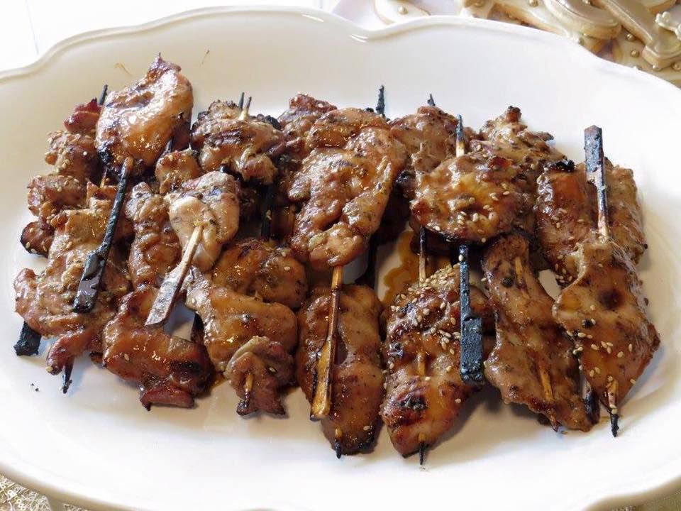 A white plate topped with meat on skewers