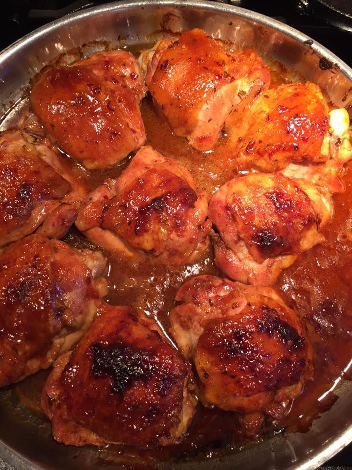 Chicken thighs are being cooked in a pan on a stove.