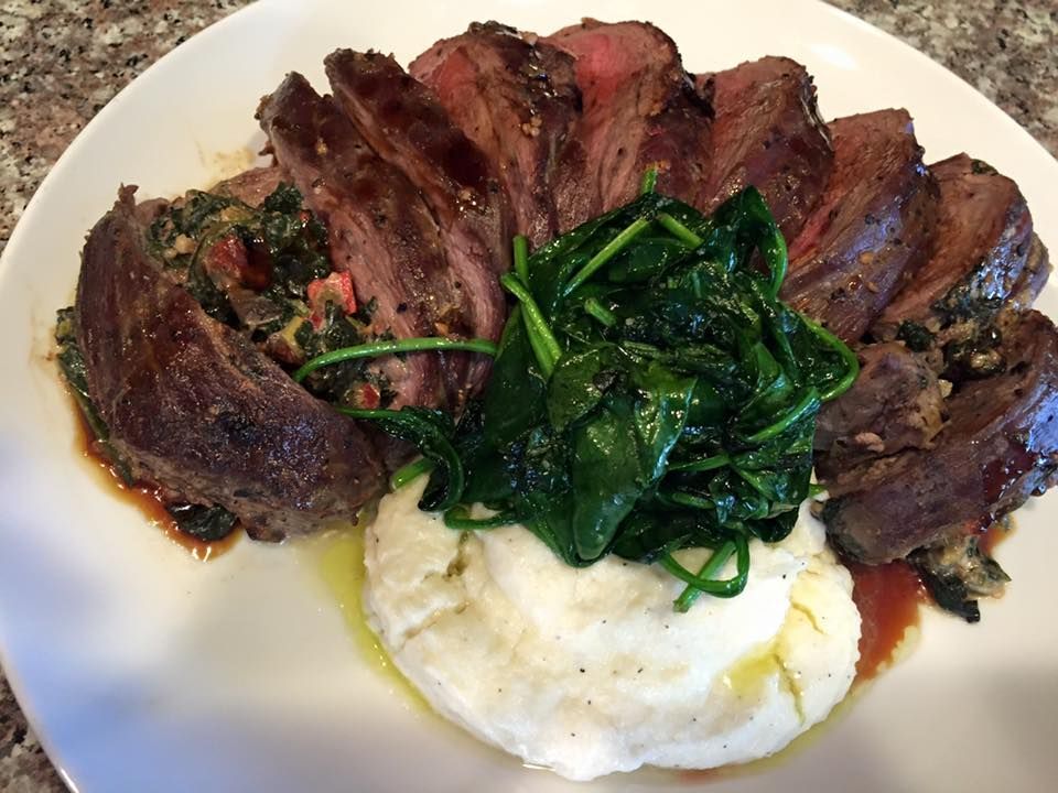 A white plate topped with meat mashed potatoes and spinach
