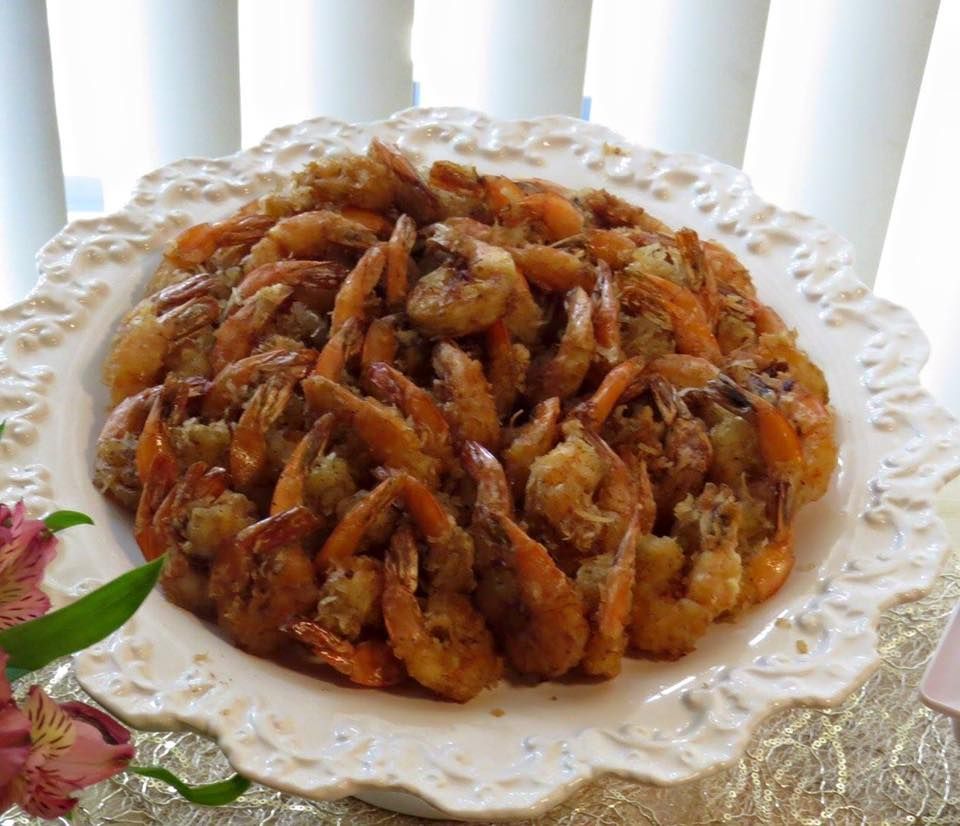 A white plate topped with fried shrimp next to a flower