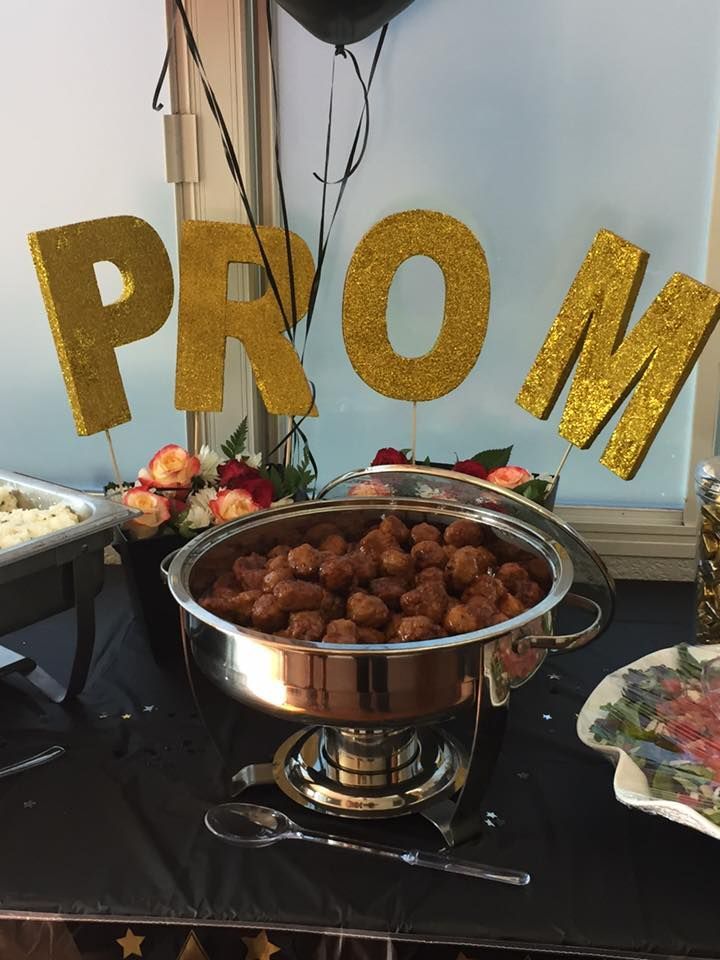 A buffet table with a bowl of food and a sign that says prom