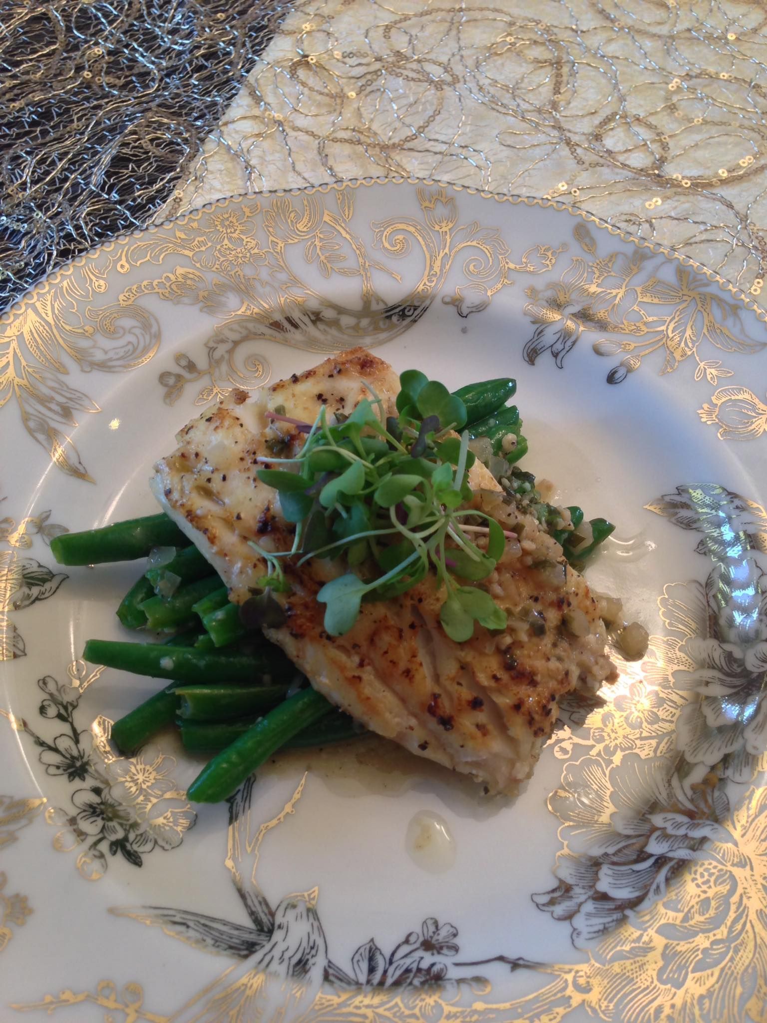 A white plate topped with a piece of meat and green beans.