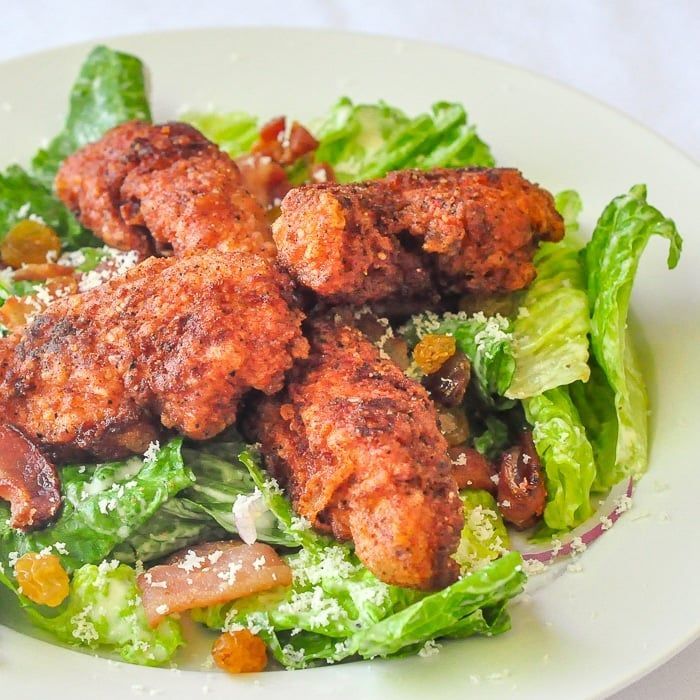 A white plate topped with fried chicken and lettuce on a table.