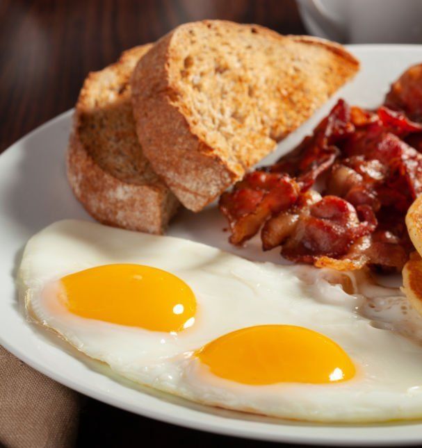 A white plate topped with eggs bacon and toast