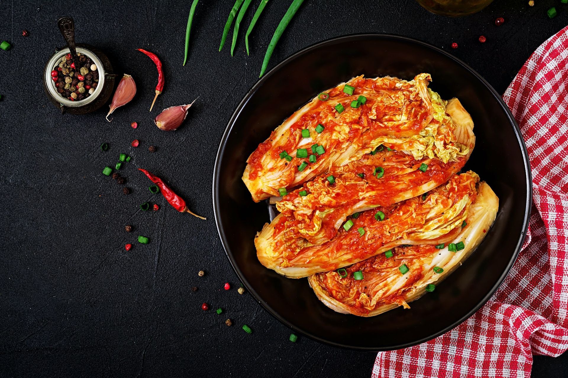 A bowl of food with vegetables and spices on a table.