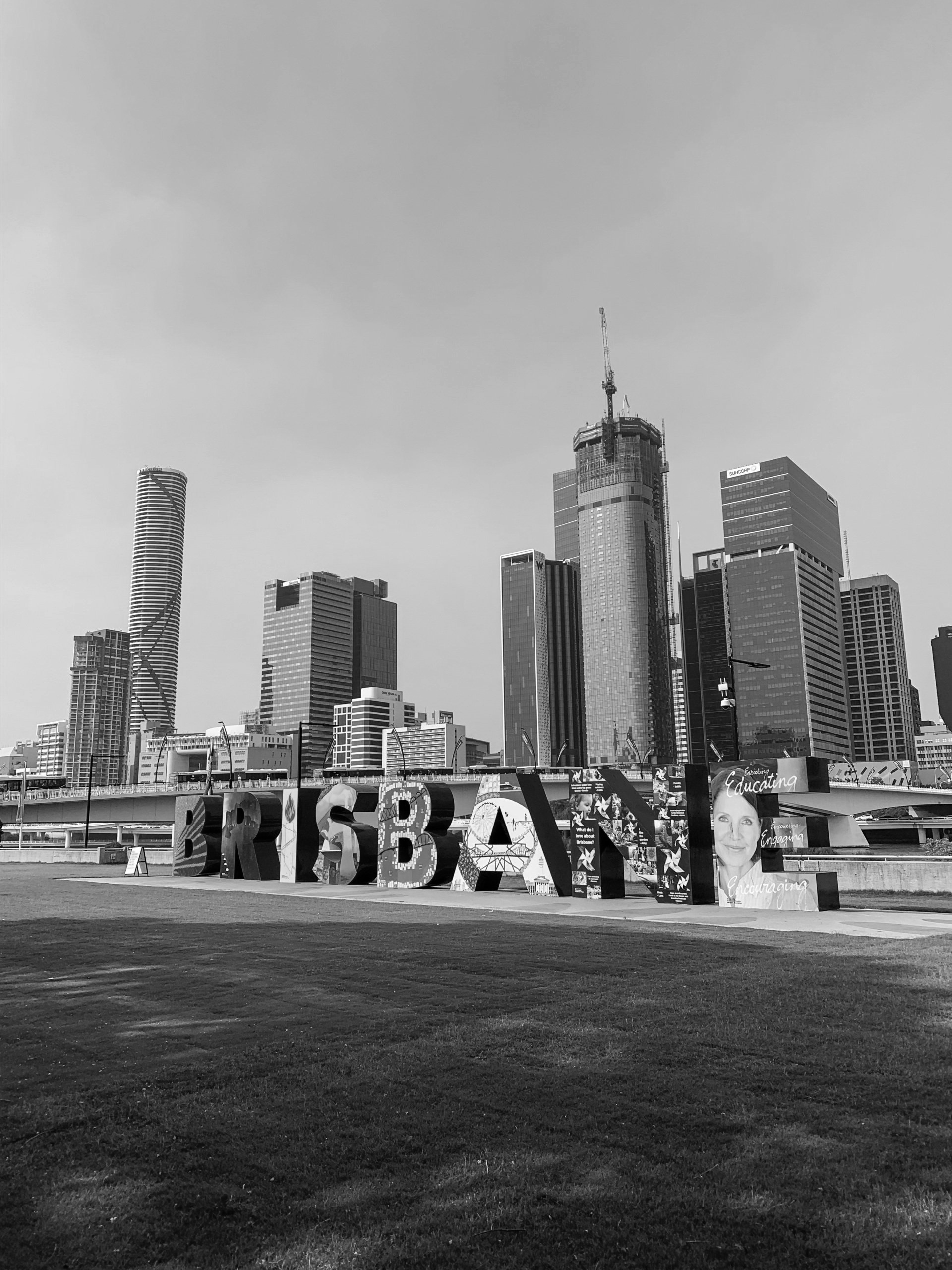 Placa de Brisbane em frente ao horizonte da cidade. Fotografia em preto e branco.