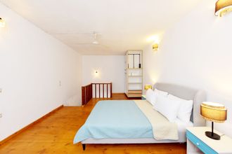 A bedroom with a bed , nightstand , lamp and stairs.