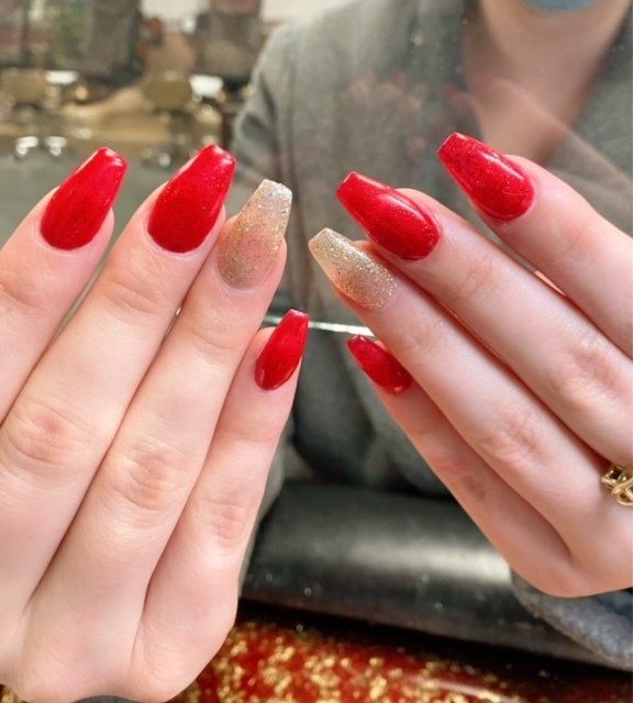 Hands with red and glitter gold coffin-shaped nails.