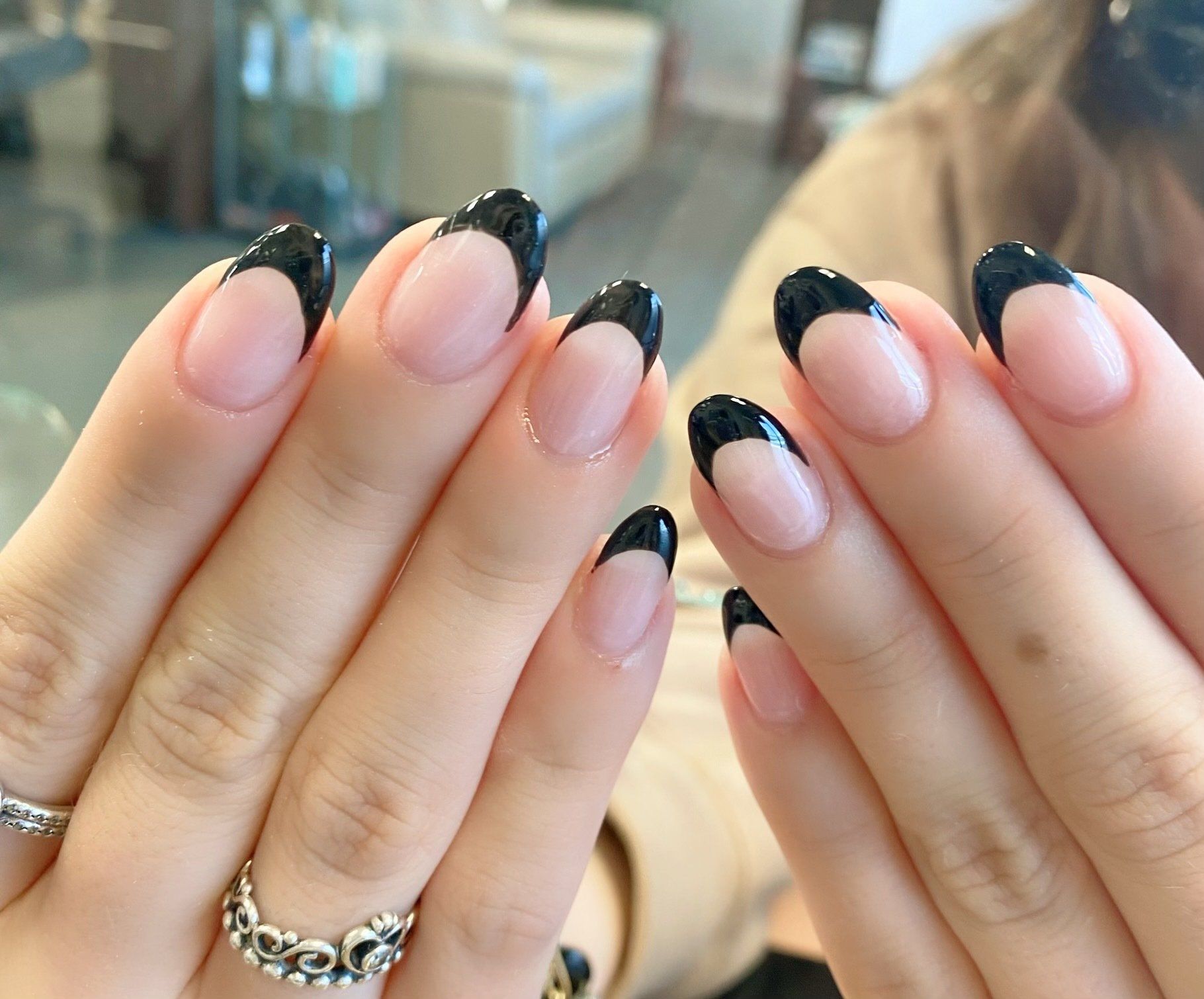 Hands with oval nails, French manicure with black tips and clear base.
