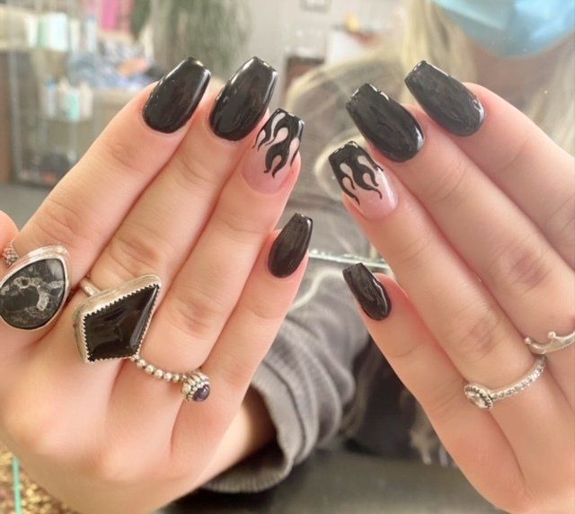 Hands with black coffin-shaped nails, one with flame design, adorned with silver rings.