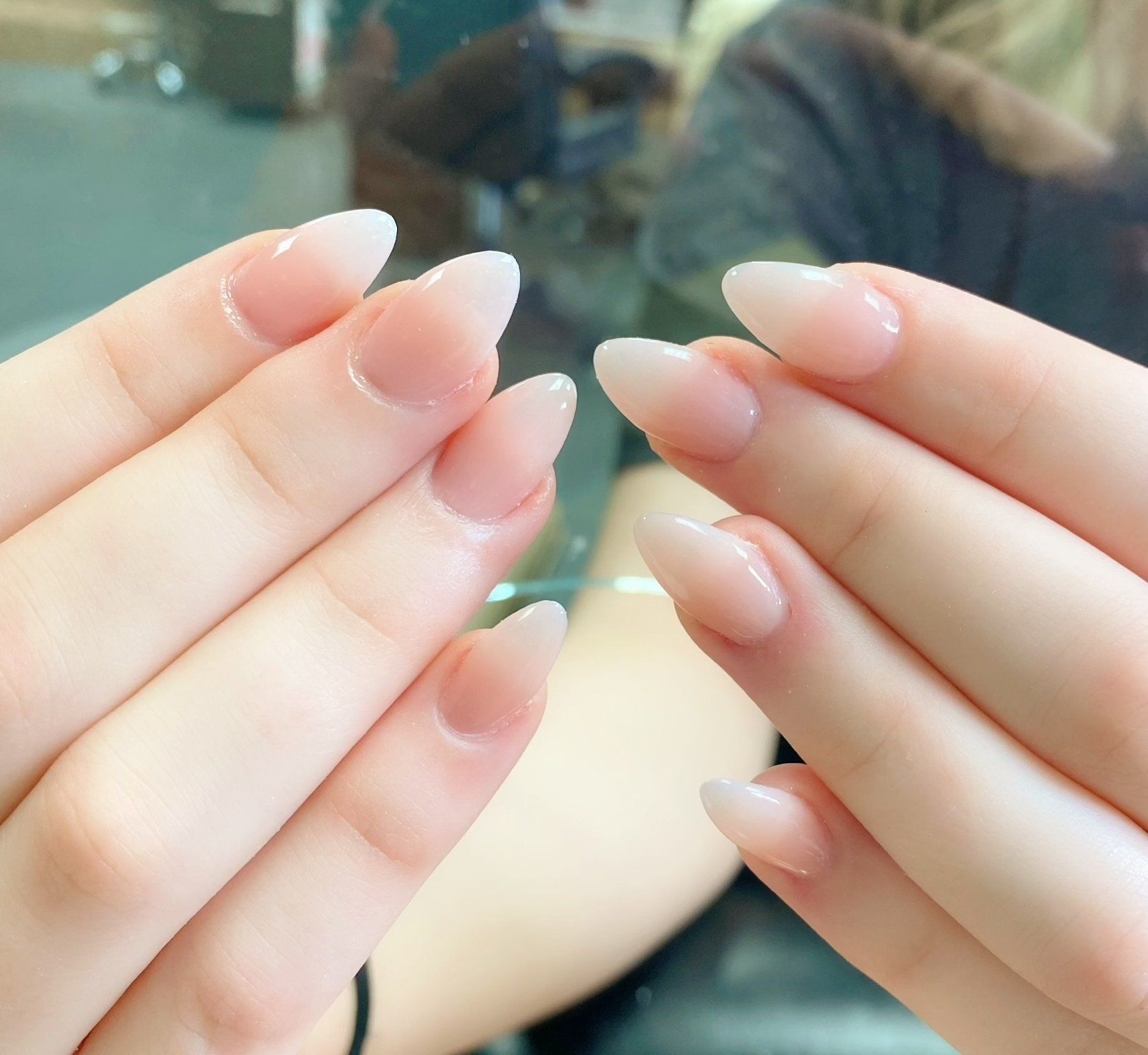 Hands with almond-shaped nails in a soft, nude gradient.