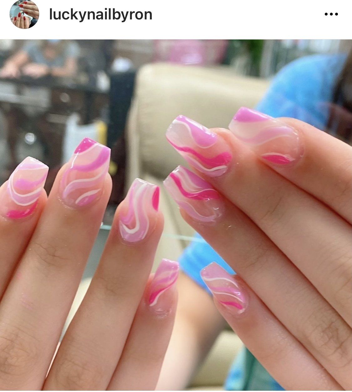 Pink and white swirled nail art on a person's hand.