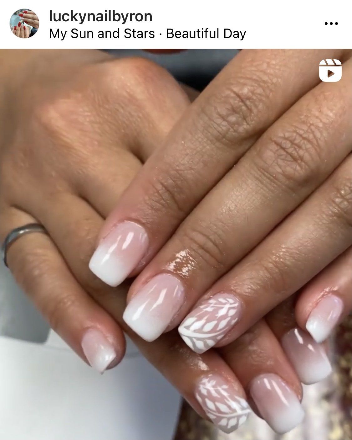 Manicured nails with white ombre, one accent nail with white leaf design.