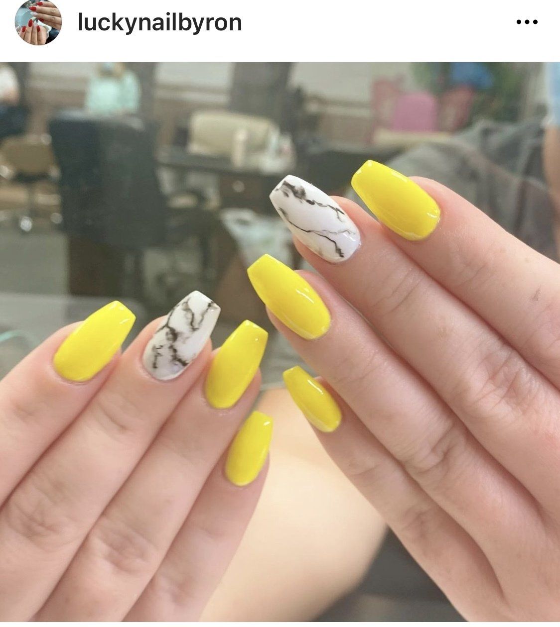 Yellow coffin-shaped nails with marble accent nails.