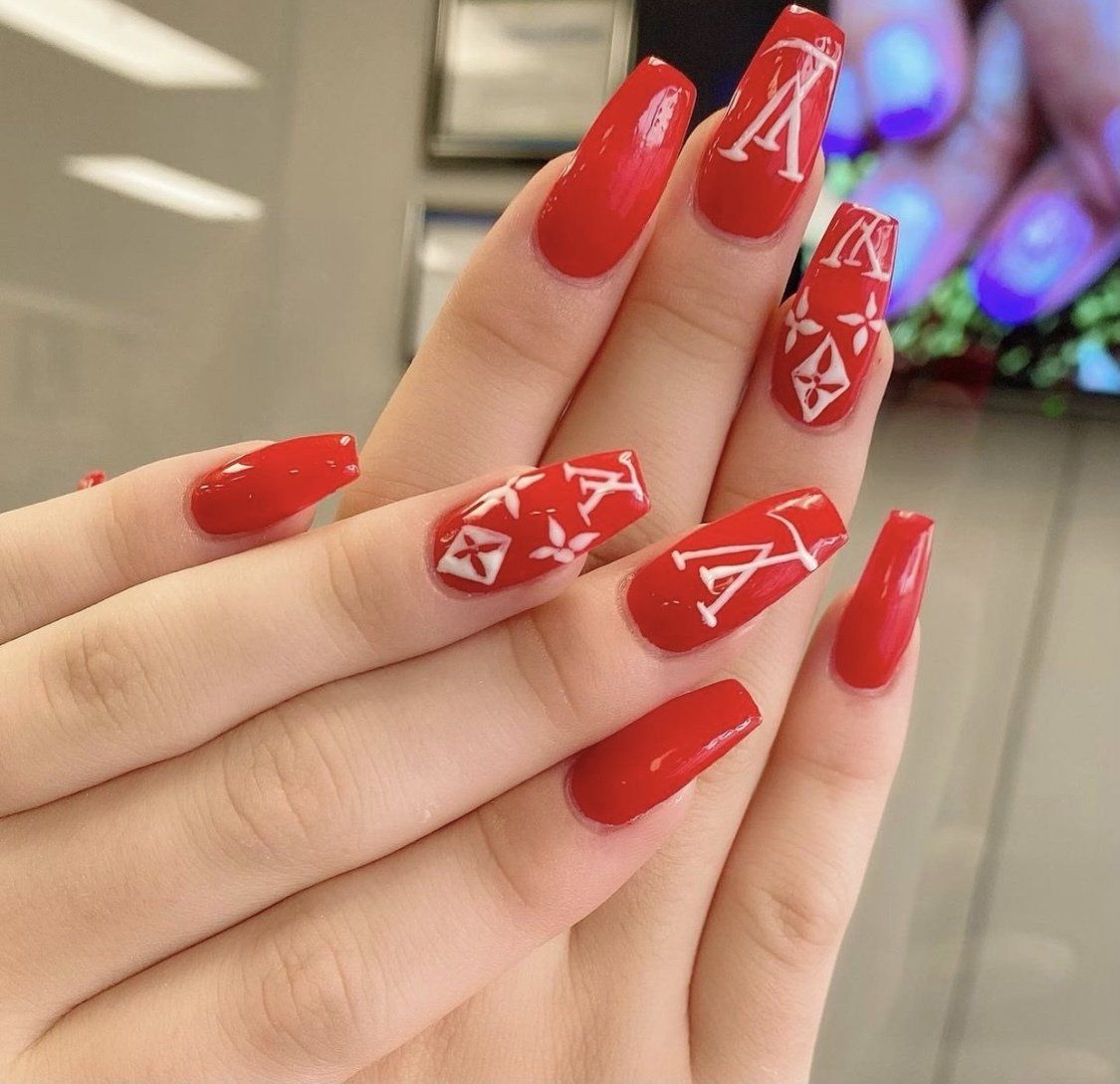 Red nail design with white Louis Vuitton logo on some nails.