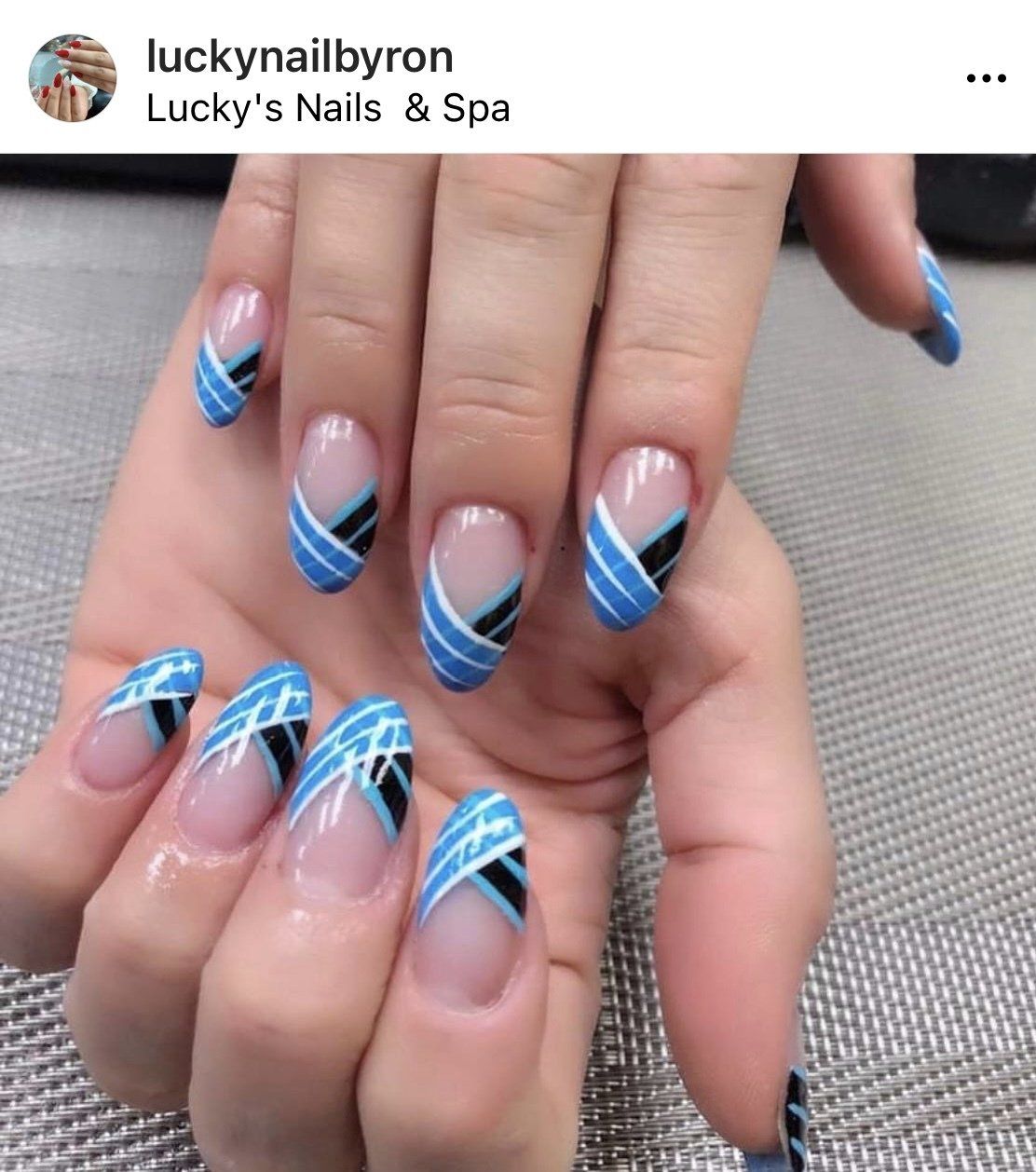 Hand with oval-shaped nails. Clear base with blue and black geometric designs.